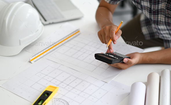Architects are using a calculator to estimate the cost of house plans. - Stock Photo - Images