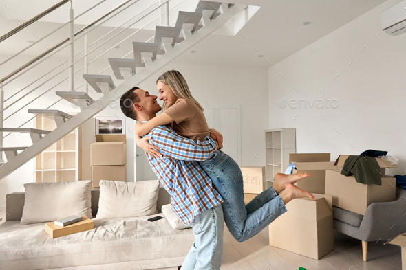Happy young couple first time home owners hugging in living room on moving day. - Stock Photo - Images