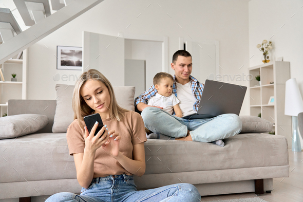 Young family with kid at home watching online movies, surfing social media.
