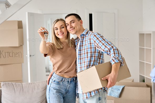 Happy young couple first time home owners holding keys in new home. - Stock Photo - Images