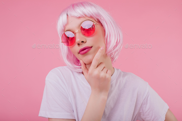 Pensive charming girl with pink hair looking up while posing on pastel ...