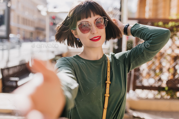 Lovable girl with dark hair walking down the street with smile. Outdoor ...