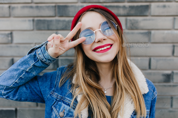 Stunning girl in cute round glasses posing on brick background ...