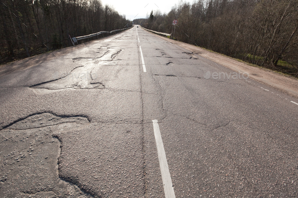 Bad quality road with potholes. Hole in asphalt. Pit, unsafe, hole road. Transportation