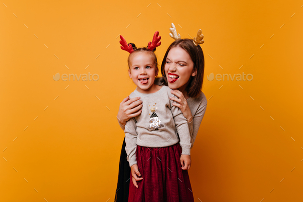 Cool Mom and her active daughter, in ears of New Year\'s deer of different colors, having fun in fro