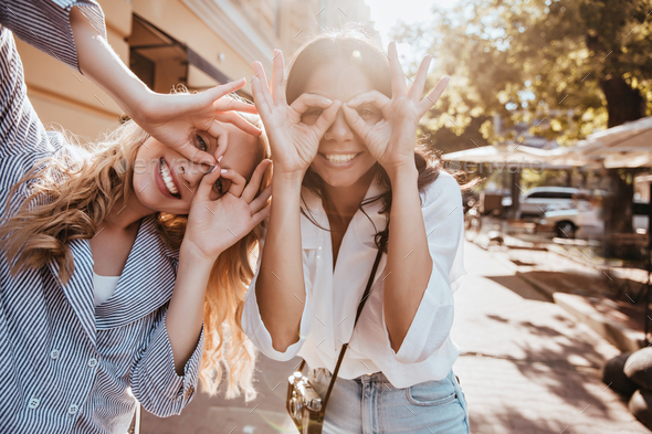 Adorable girls posing on the street in sunny spring day. Good-humoured ...