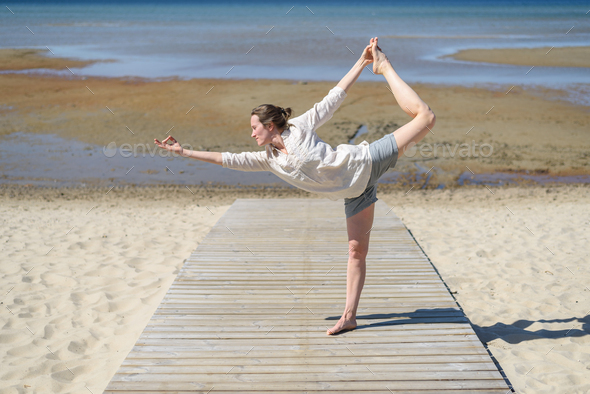 Full length of woman practicing yoga in tree pose at beach from Pikwizard