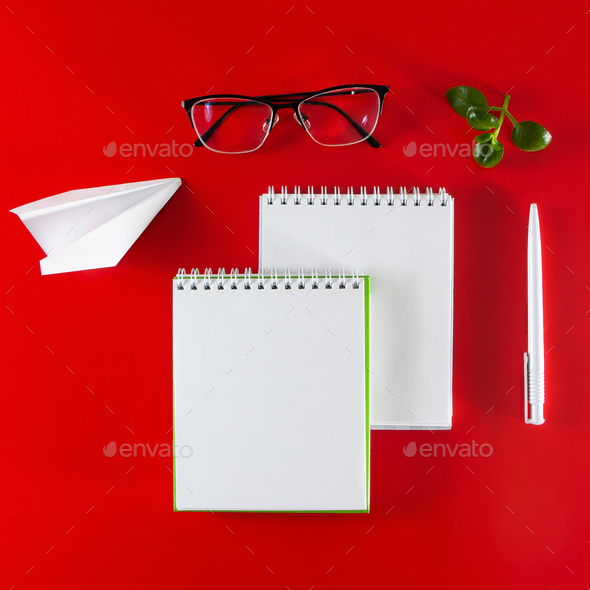 Office on a red background. Blank notebook, pen and glasses. Stock Photo Statuska