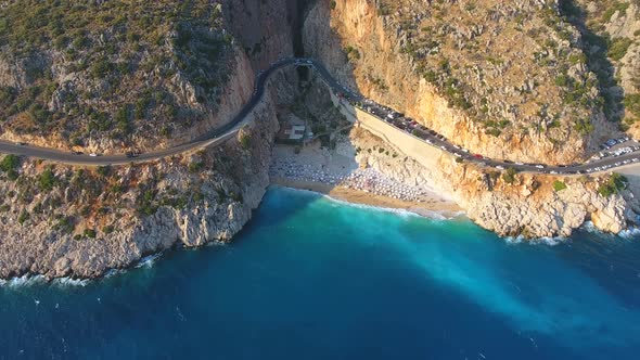 People Swim on Light Blue Sea in the White Sandy Beach Near the Rocky Mountainside alt