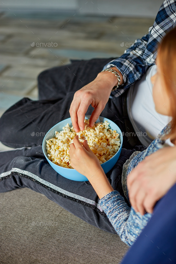 Father and daughter eat popcorn and watch TV film