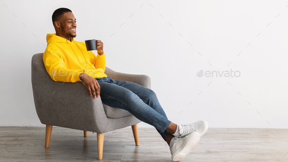 African Guy Drinking Coffee Sitting In Chair Over Gray Background Stock  Photo by Prostock-studio