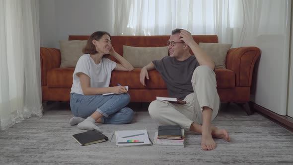 A Guy and a Girl Communicate and Laugh While Studying at Home with Textbooks Students