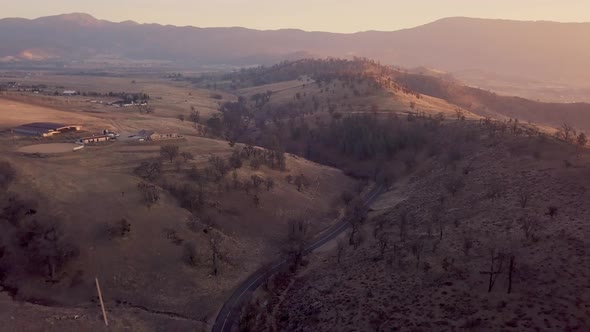 Aerial pull back of winding road in California Tehachapi mountains at sunrise alt