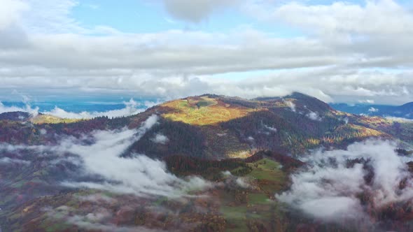 Fly Over Landscapes of Green Hills Under a Layer of White and Fluffy Clouds alt