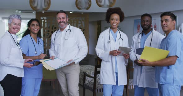 Portrait of diverse male and female doctors standing in hospital corridor smiling to camera alt
