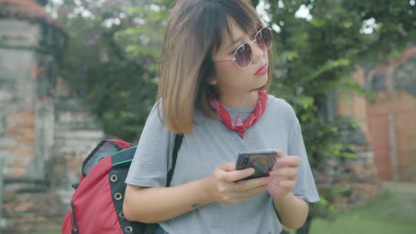Asian woman using smartphone for direction and looking on location map while spending holiday alt