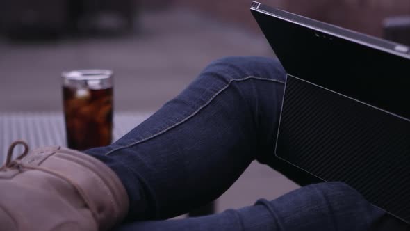 Panning view from womans feet to face while typing on laptop. alt