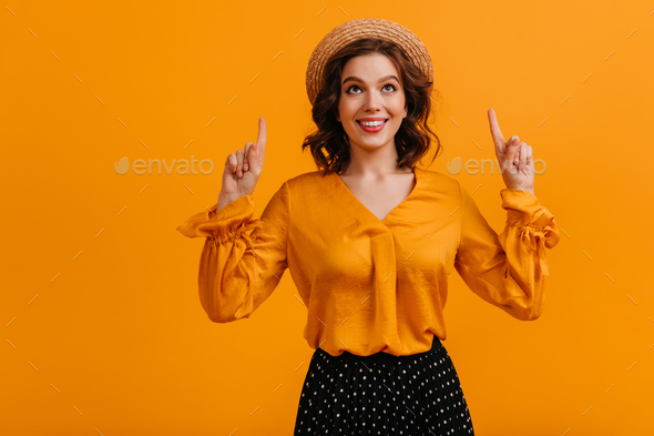 Glad girl in boater pointing with fingers. Studio shot of ecstatic lady in vintage hat.