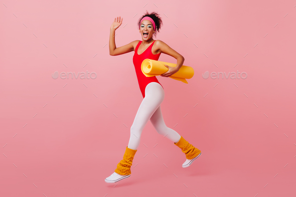 Appealing african woman in aerobics outfit running on pink