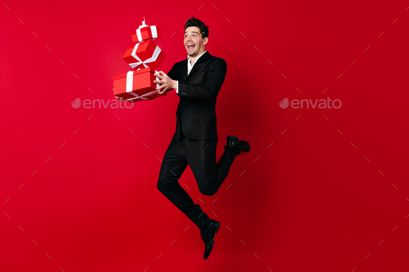 Joyful man celebrating birthday. Studio shot of positive male model jumping with presents.