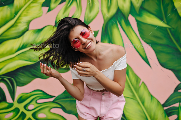 Excited woman with tattoo laughing in front of graffiti. Attractive girl expressing happiness in su