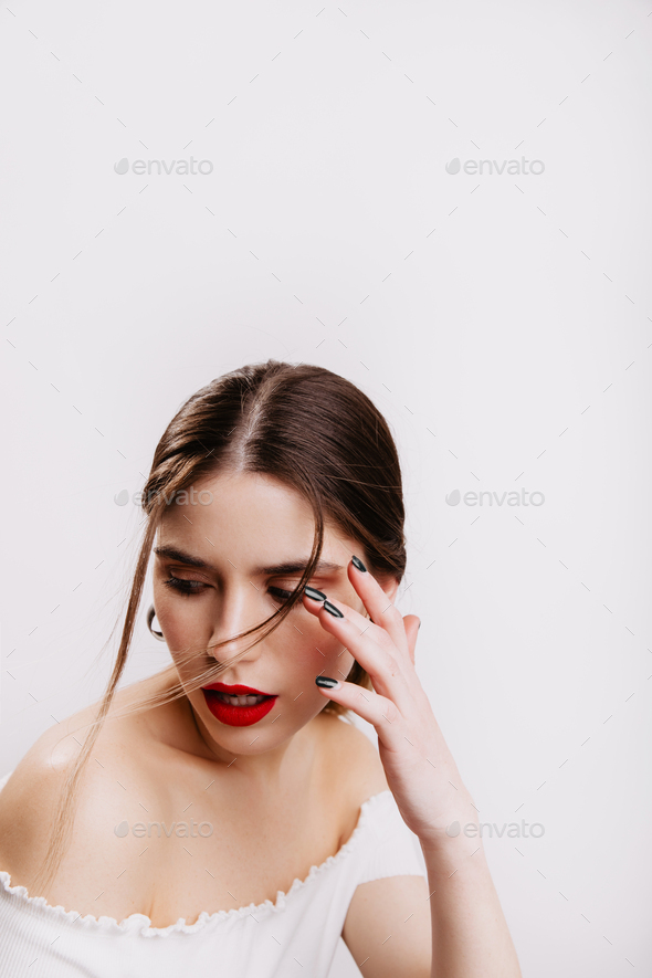Closeup portrait of girl with perfect skin tone and red lips playing hair on white background