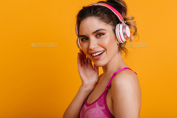 Fascinating fitness girl listening music. Indoor portrait of smiling woman doing sports