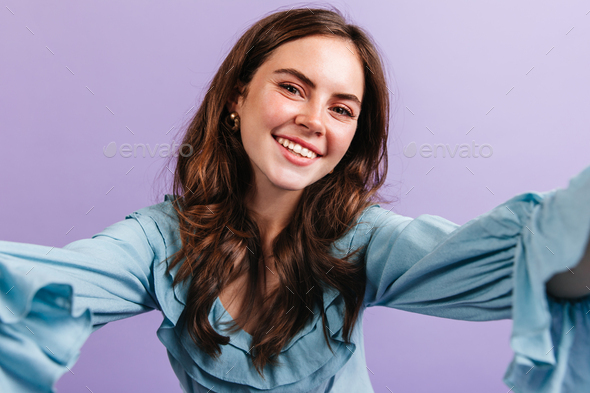 Green-eyed girl in high spirits looks into camera. Selfie of young brunette with snow-white smile a - Stock Photo - Images