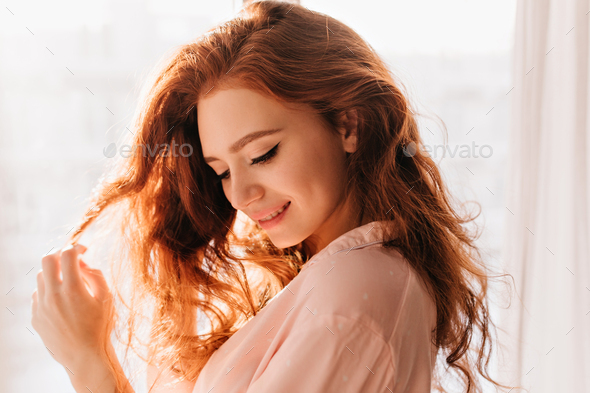 Attractive slim girl with light hairstyle chilling in modern apartment.  Fashionable young woman in b Stock Photo by look_studio