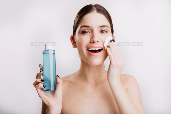 Beautiful woman delicately moisturizes skin with cosmetic tonic. Portrait of lady with healthy skin