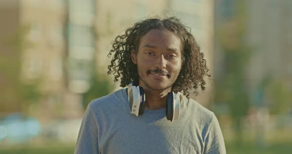 Portrait a Handsome Guy with Long Hair and Headphones Smiles