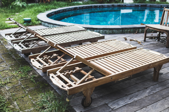Wooden recliners near swimming pool in luxury resort. Wooden floor and outdoor furniture