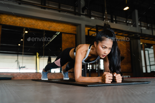 Asia lady exercise doing plank fat burning workout in fitness class. Athlete with six pack,