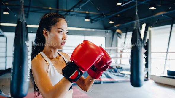 Young Asia lady kickboxing exercise workout punching bag tough female  fighter practice boxing in gym fitness class. Sportswoman recreational  activity, functional training, healthy lifestyle concept. Stock Photo