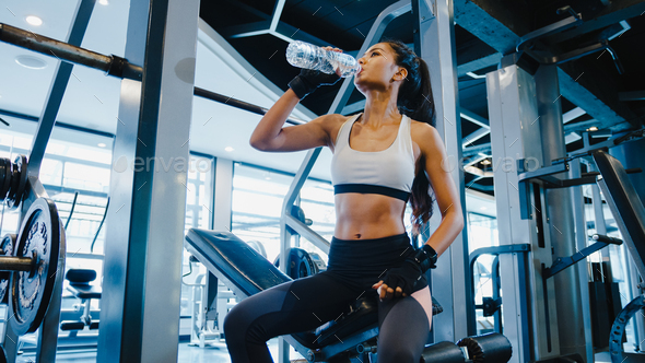 Asia lady exercise drinking water after fat burning workout in fitness  class. Stock Photo by Tirachard