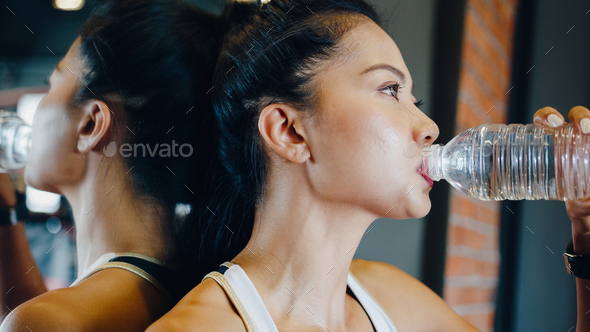 Asia lady exercise drinking water after fat burning workout in fitness class.