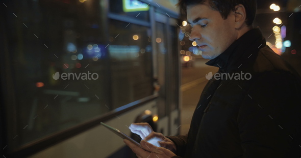 Man Writing Letters in Tablet PC while Waiting for the Bus