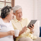 Asian elderly couple using tablet and drinking coffee in living room at home. - PhotoDune Item for Sale