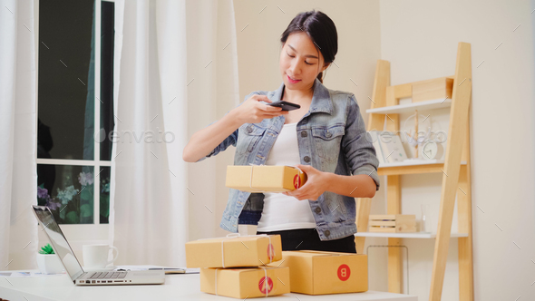 Asian young entrepreneur business woman owner of SME checking product on stock scan qr code.