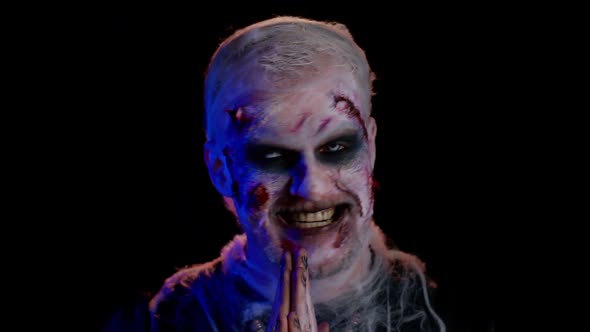 Scary Wounded Undead Man with Bloody Scars Face Making Faces Looks at Camera and Smiles Terribly alt