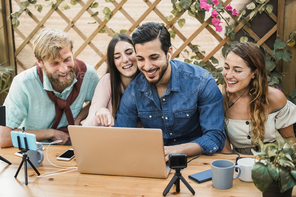 Young people streaming online using laptop computer and mobile phone camera outdoor - Stock Photo - Images