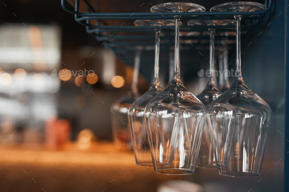 Wineglasses hanging on glass drying rack Stock Photo by seventyfourimages