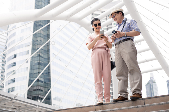 Senior Asian couple playing mobile outdoors. - Stock Photo - Images