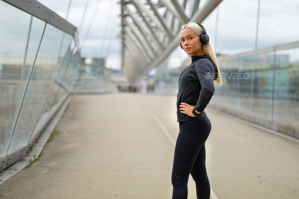 Woman in Black Workout Outfit Standing At Modern Bridge In City Stock Photo  by kjekol