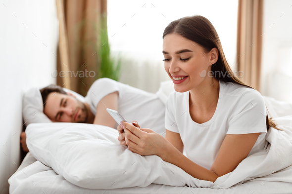Cheating Wife Texting On Phone While Husband Sleeping In Bedroom