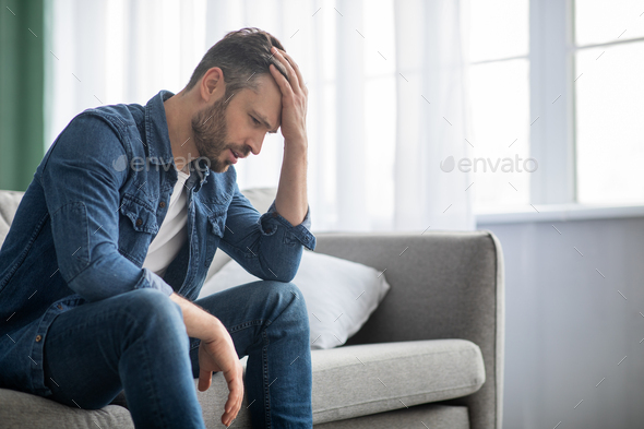 Pensive man sitting on couch at home, side view Stock Photo by Prostock ...