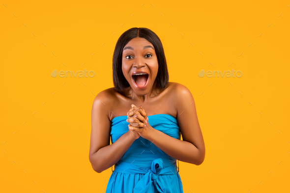 Overjoyed black lady shouting OMG, clasping her hands together, excited over huge summer sale on