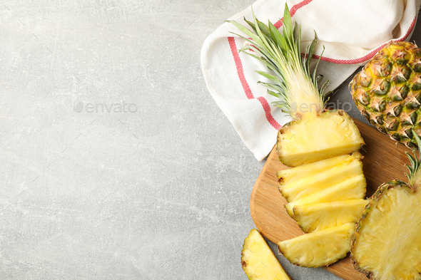 Cutting board with pineapples on grey background, top view Stock Photo