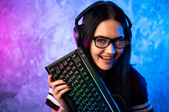 Young teen gamer wearing glasses standing posing with computer gaming equipment - Stock Photo - Images