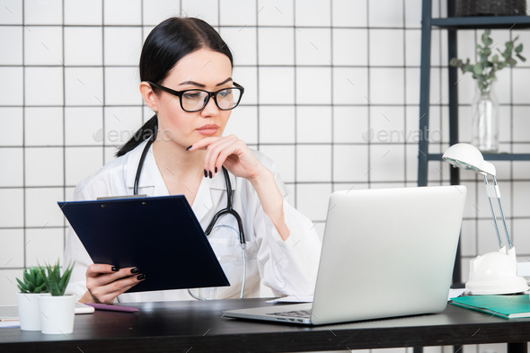 Female brunette doctor wears glasses using tablet, intelligent and lovely woman with the gadget and - Stock Photo - Images